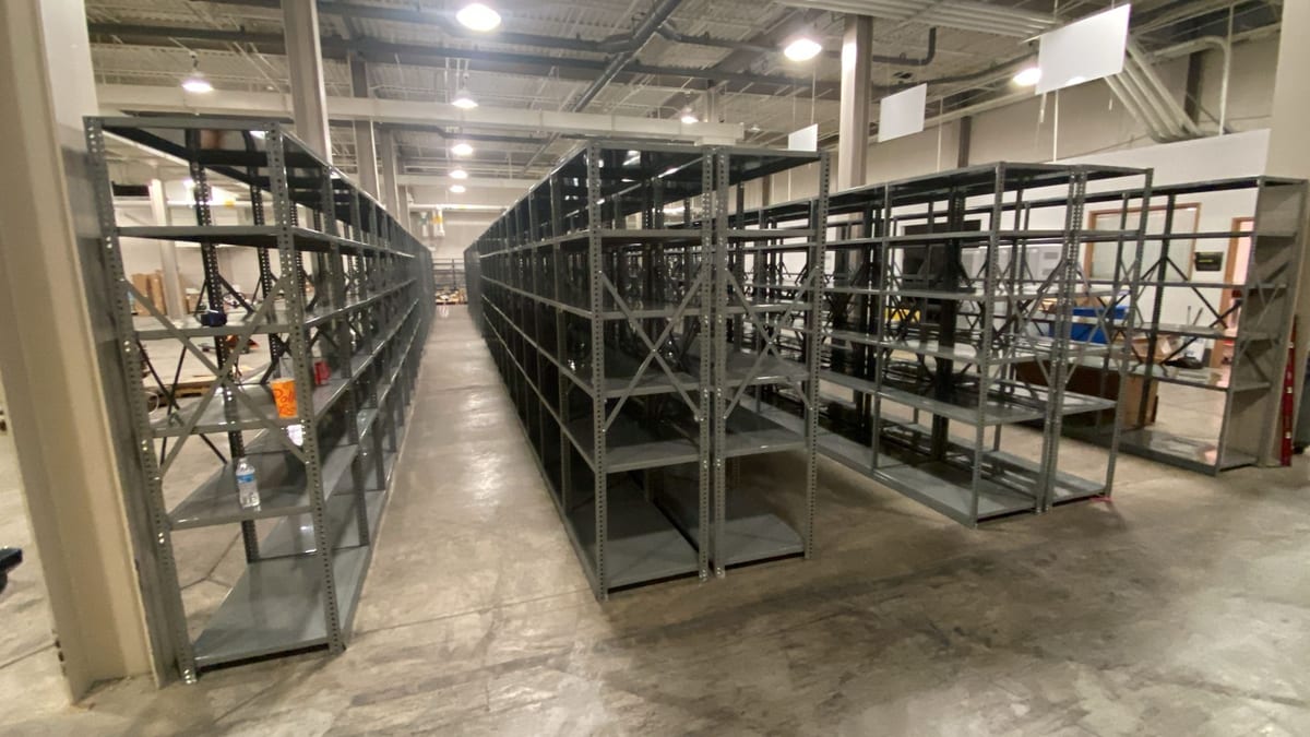 Long rows of gray industrial clip shelving in a water district parts and materials storeroom